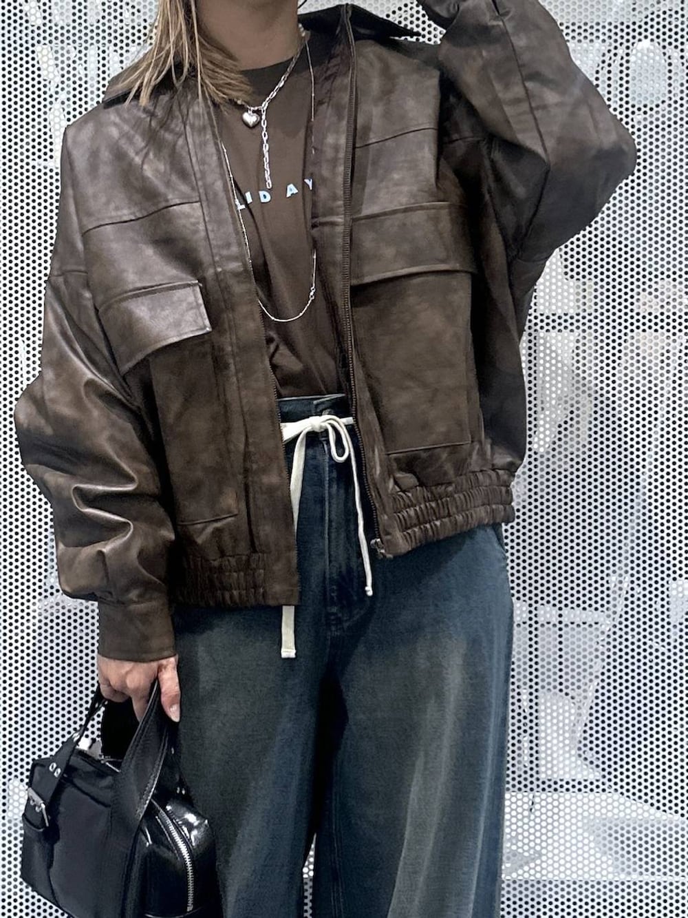 ブラウン系のブルゾン、ブラック系のショルダーバッグ、ブルー系のデニムパンツを着用したレディースの秋コーディネートの4枚目の写真