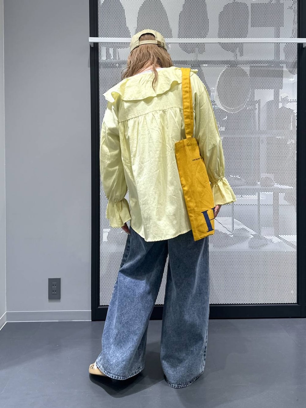 イエロー系のトートバッグ、ブルー系のデニムパンツ、ベージュ系のスニーカーを着用したレディースの春コーディネートの3枚目の写真