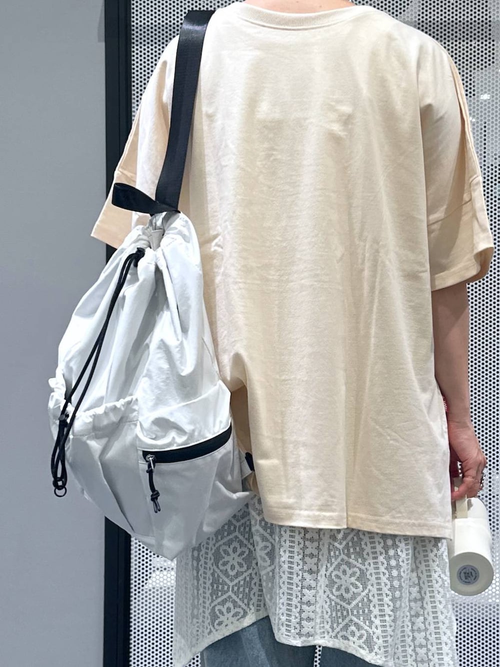 ホワイト系のショルダーバッグ、ブルー系のデニムパンツ、ベージュ系のワンピースを着用したレディースの夏コーディネートの6枚目の写真