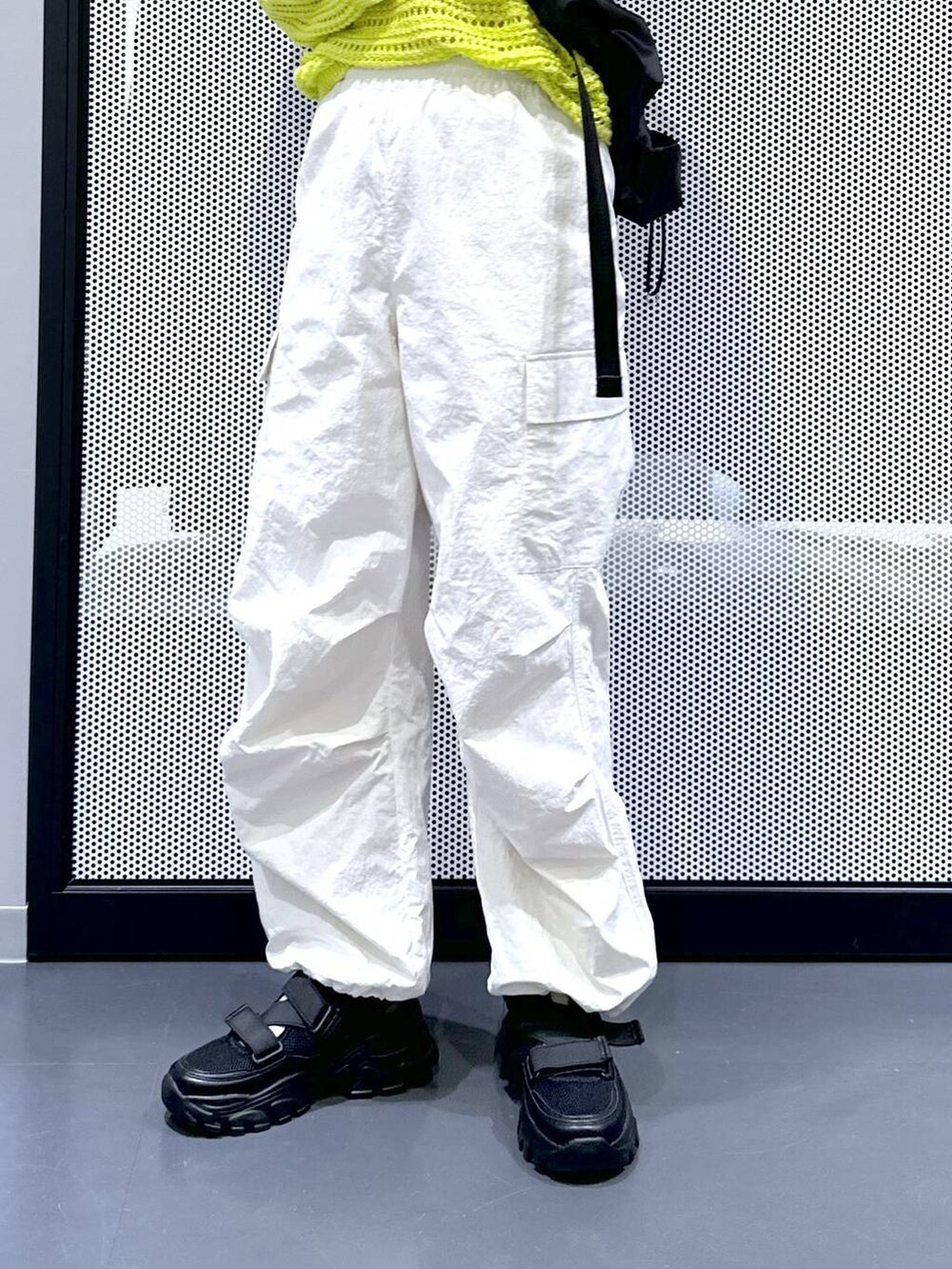 ブラック系のスニーカー、ホワイト系のカーゴパンツ、グリーン系のニット/セーターを着用したレディースの春コーディネートの5枚目の写真