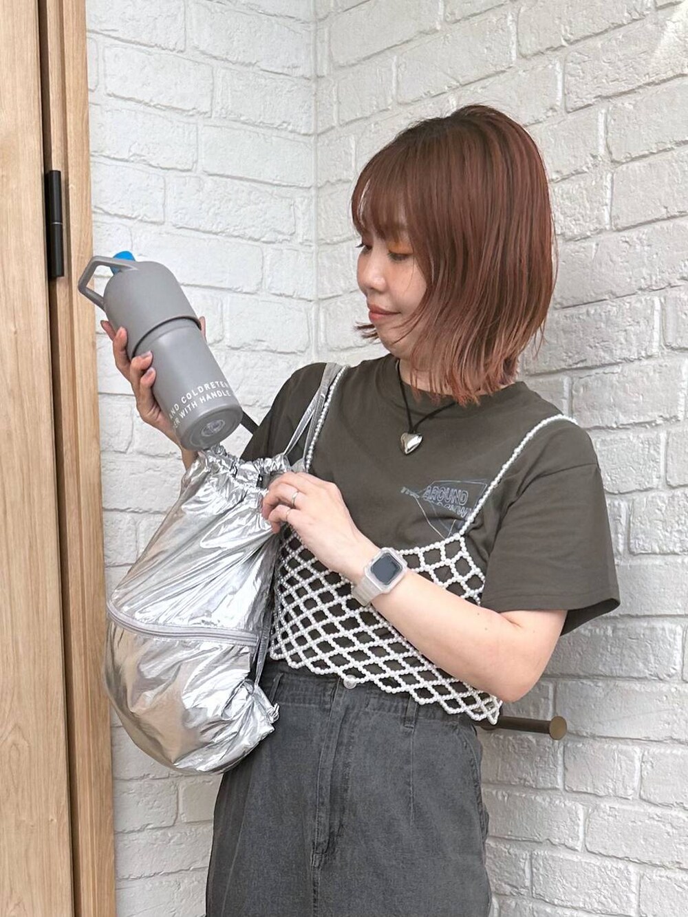 グレー系のデニムスカート、シルバー系のバックパック/リュック、ブラック系のサンダルを着用したレディースの春コーディネートの2枚目の写真