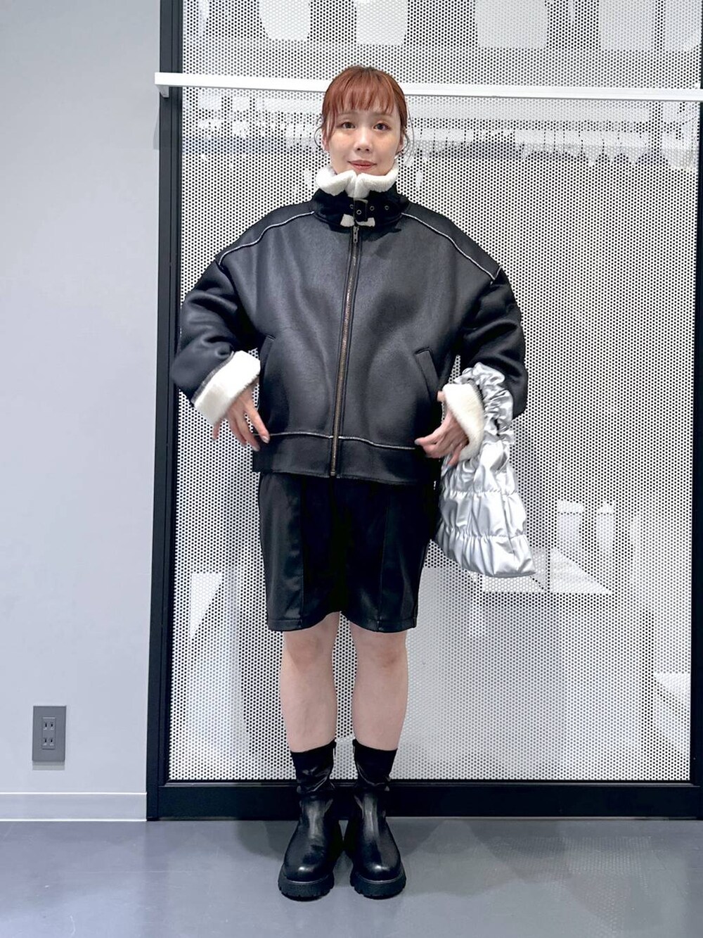 ブラック系のブルゾン、ブラック系のブーツ、シルバー系のショルダーバッグを着用したレディースの秋コーディネートの2枚目の写真