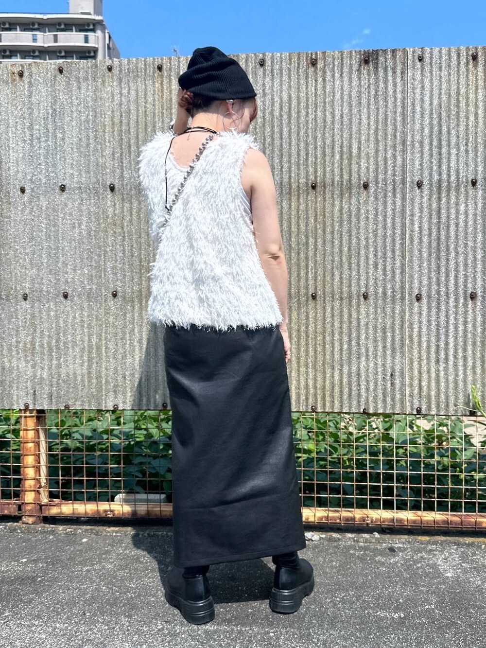 ブラック系のスカート、ブラック系のブーツ、ベージュ系のベストを着用したレディースの秋コーディネートの3枚目の写真