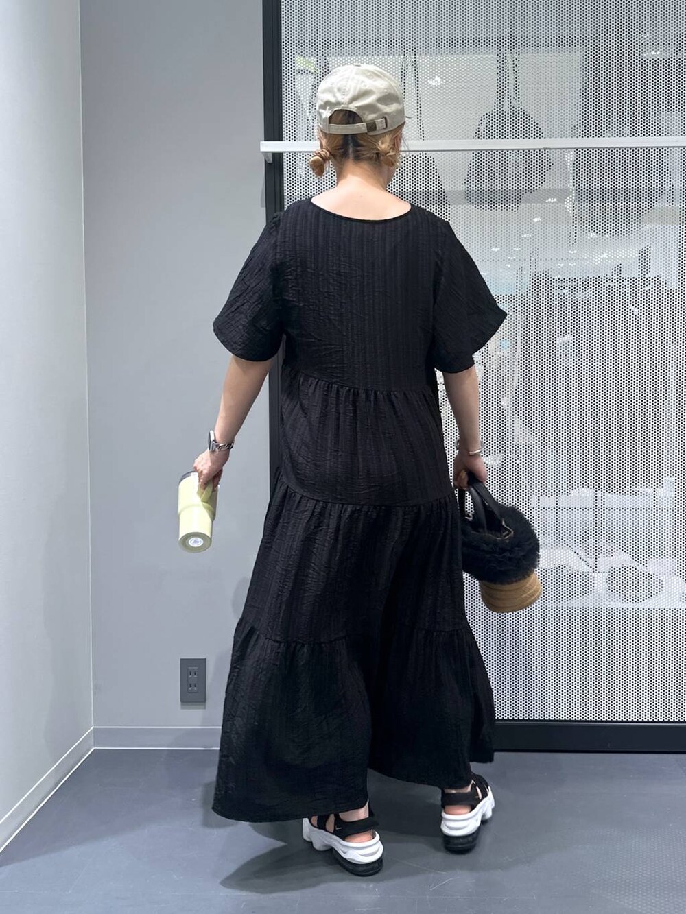 ベージュ系のショルダーバッグ、ブラック系のワンピース、ブラック系のサンダルを着用したレディースの春コーディネートの3枚目の写真