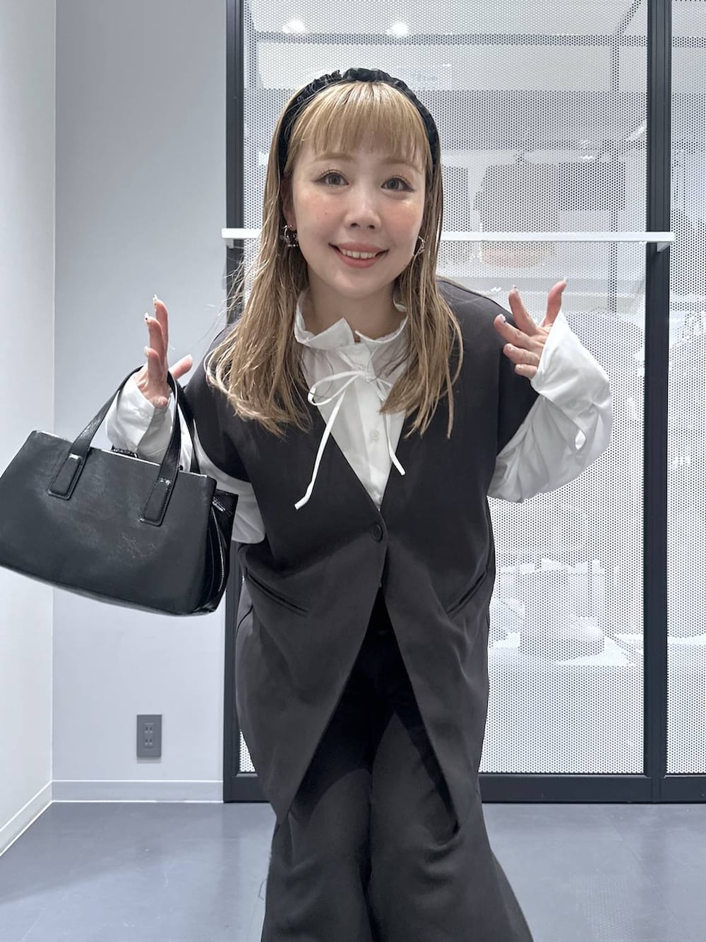 ブラック系のボストンバッグ、グレー系のスラックス、グレー系のベストを着用したレディースの冬コーディネートの2枚目の写真