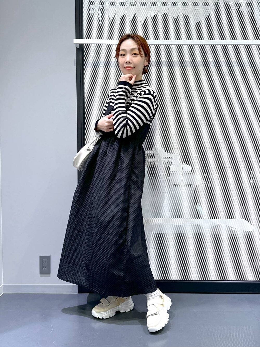 ベージュ系のスニーカー、ブラック系のワンピース、ホワイト系のショルダーバッグを着用したレディースの冬コーディネートの3枚目の写真