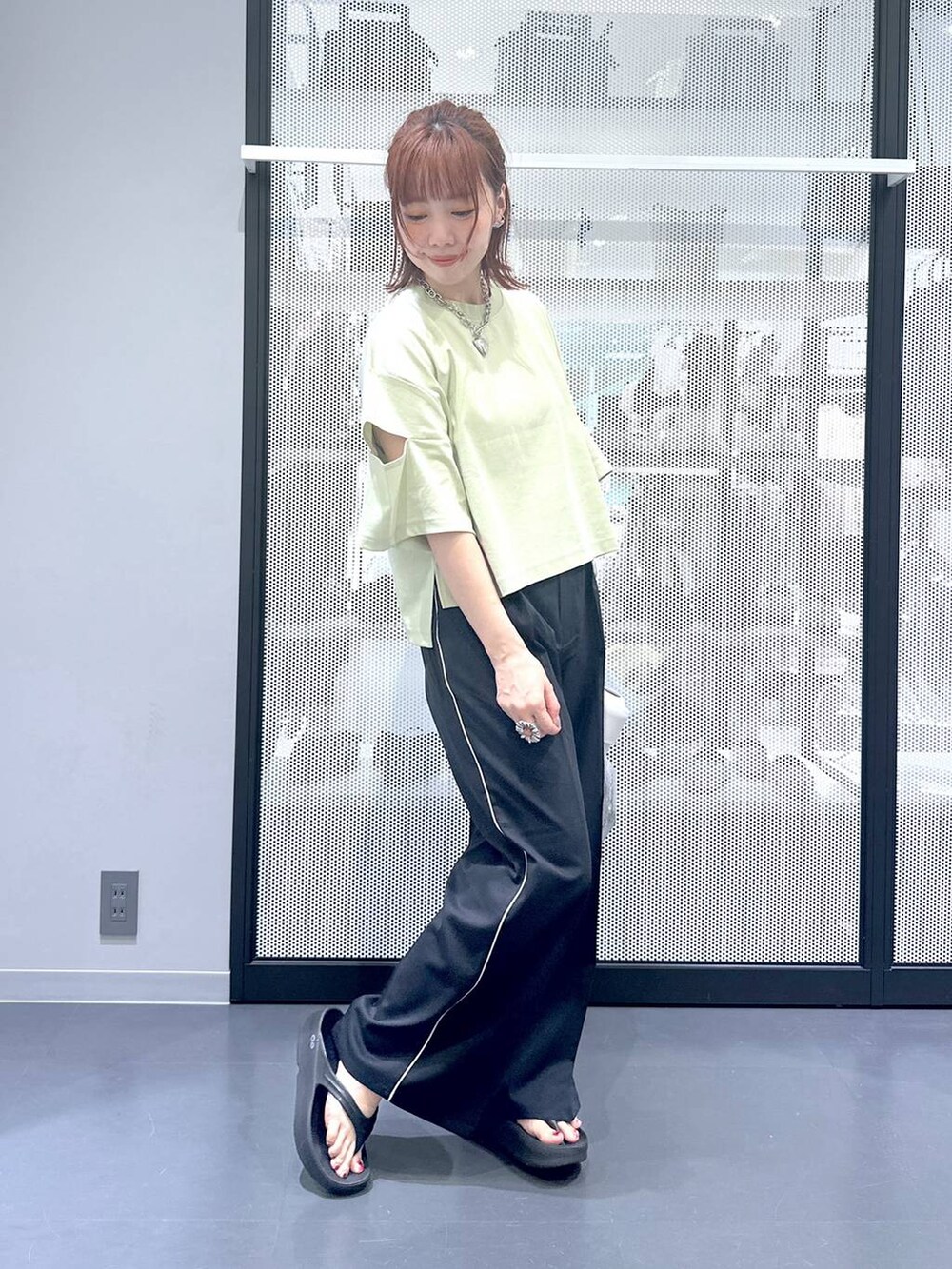 シルバー系のショルダーバッグ、グリーン系のTシャツ/カットソー、ブラック系のサンダルを着用したレディースの夏コーディネートの5枚目の写真