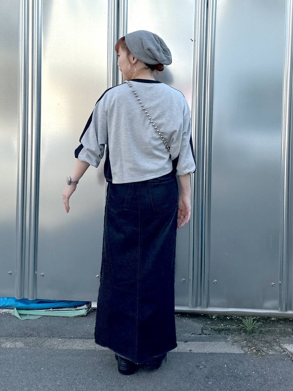 ブラック系のデニムスカート、グレー系のTシャツ/カットソー、ブラック系のブーツを着用したレディースの秋コーディネートの4枚目の写真