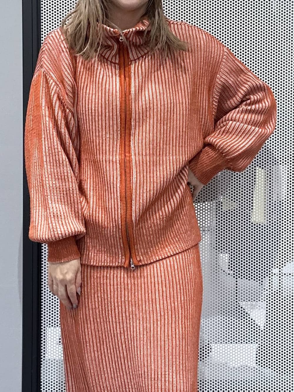 オレンジ系のスカート、オレンジ系のニット/セーター、その他のピアス（両耳用）を着用したレディースの冬コーディネートの4枚目の写真