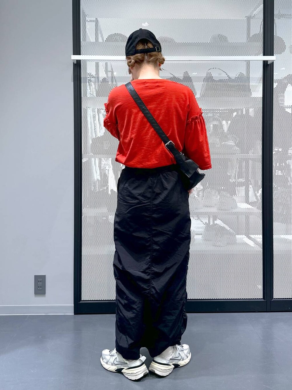 ブラック系のスカート、ブラック系のショルダーバッグ、レッド系のTシャツ/カットソーを着用したレディースの春コーディネートの3枚目の写真