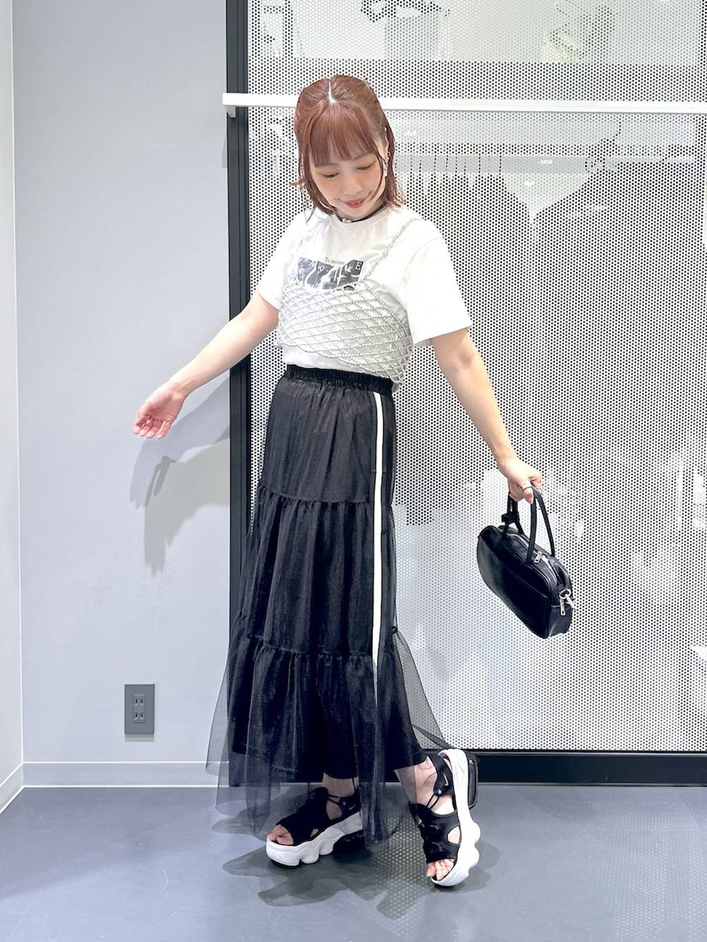 ブラック系のショルダーバッグ、ホワイト系のTシャツ/カットソー、ブラック系のスカートを着用したレディースの夏コーディネートの2枚目の写真