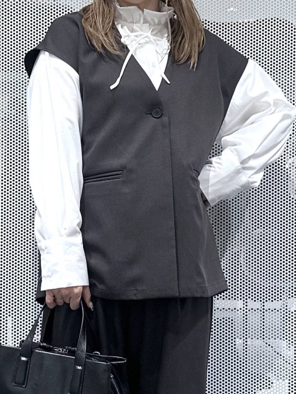 ブラック系のボストンバッグ、グレー系のスラックス、グレー系のベストを着用したレディースの冬コーディネートの4枚目の写真