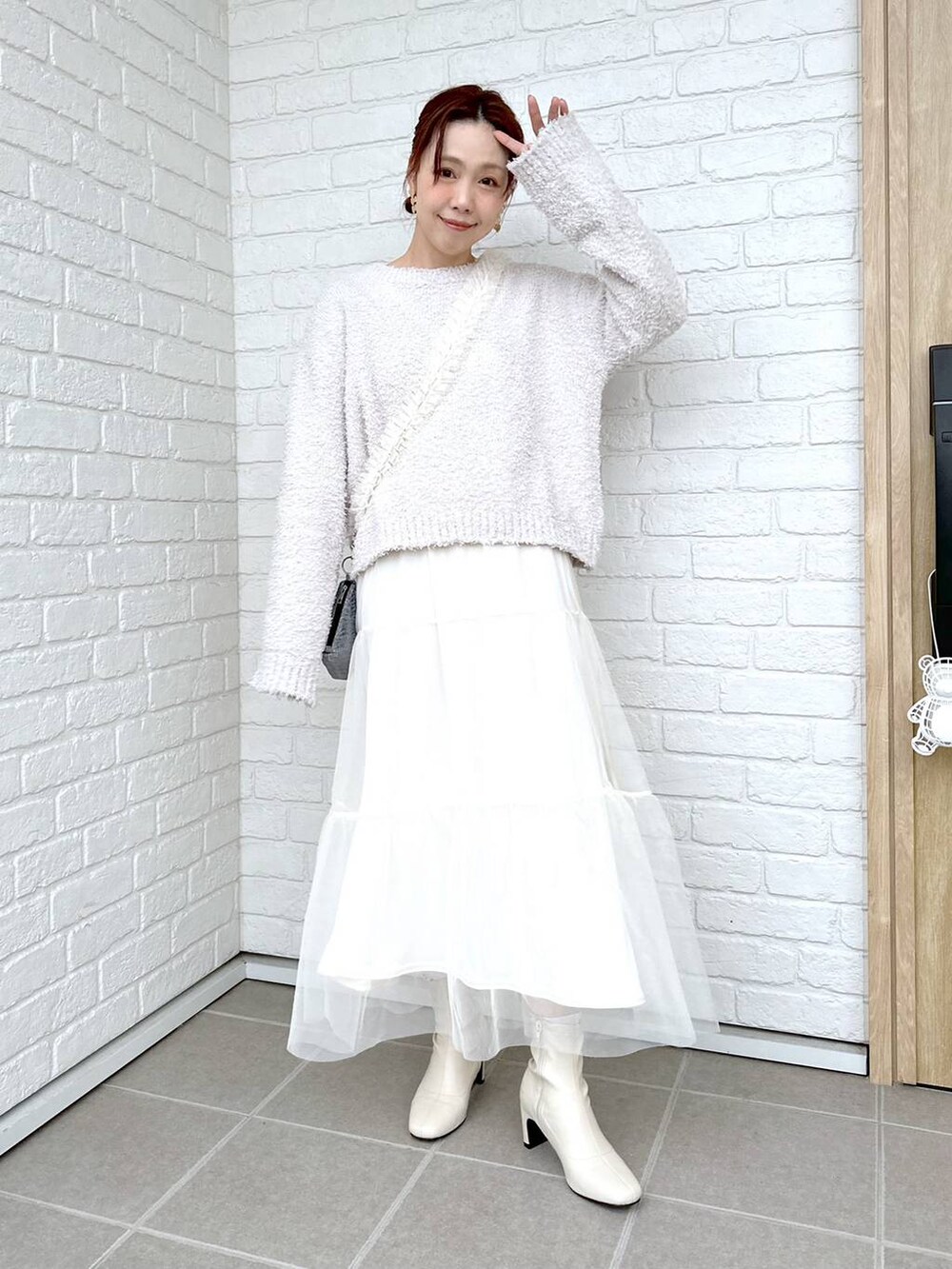 グレー系のニット/セーター、ホワイト系のブーツ、ホワイト系のTシャツ/カットソーを着用したレディースの冬コーディネートの6枚目の写真