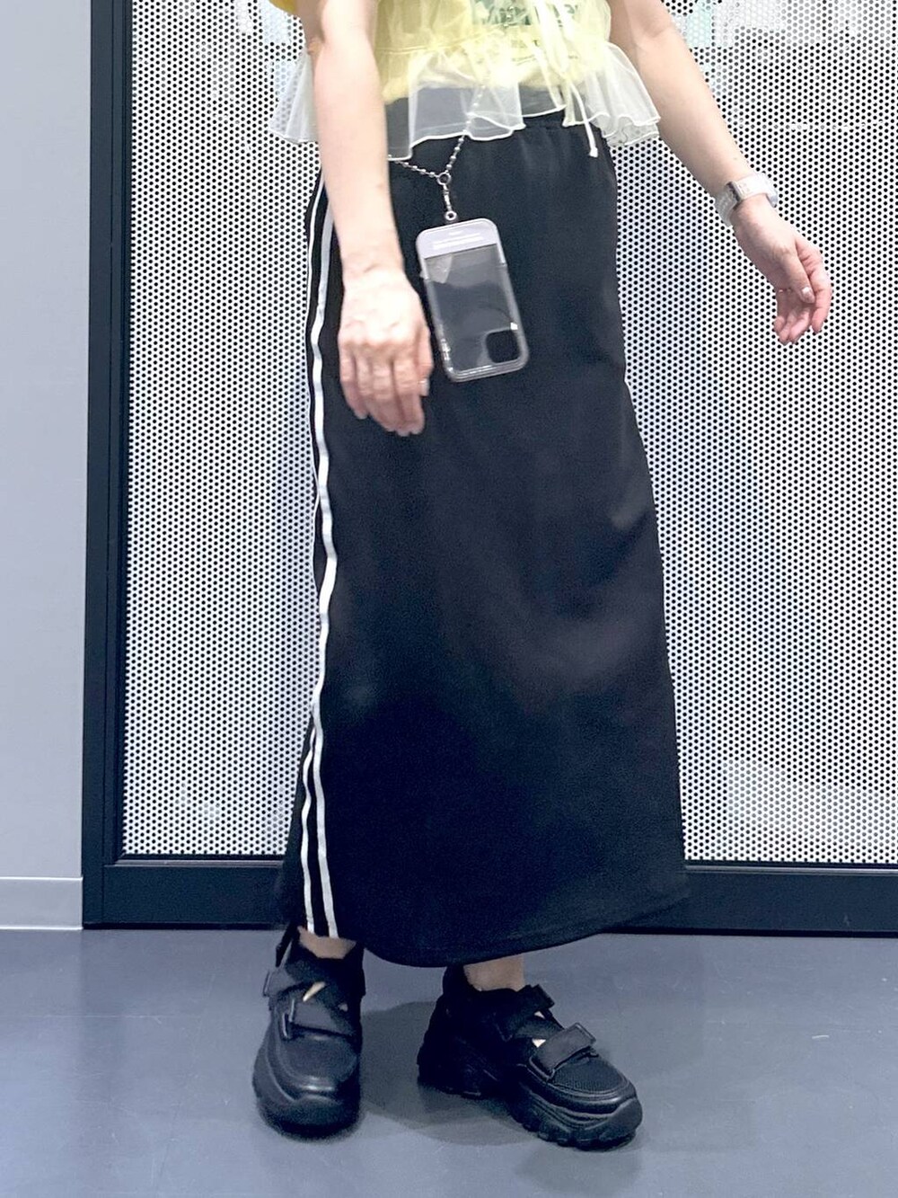 ブラック系のスカート、イエロー系のキャミソール、ベージュ系のTシャツ/カットソーを着用したレディースの春コーディネートの7枚目の写真