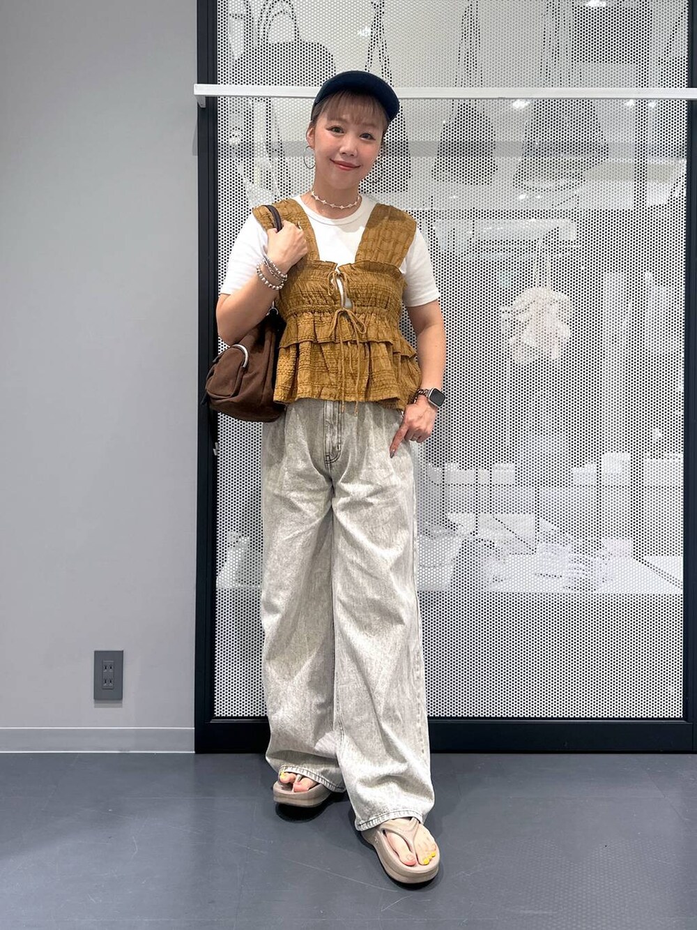 グレー系のデニムパンツ、ホワイト系のTシャツ/カットソー、ベージュ系のサンダルを着用したレディースの夏コーディネートの2枚目の写真