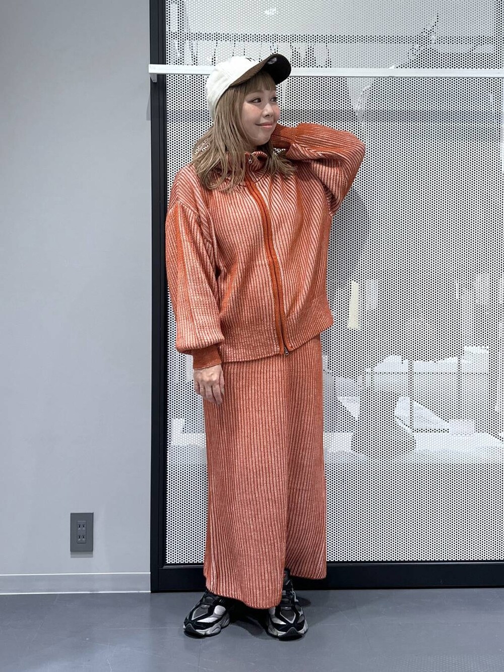 オレンジ系のスカート、オレンジ系のニット/セーター、その他のピアス（両耳用）を着用したレディースの冬コーディネートの6枚目の写真