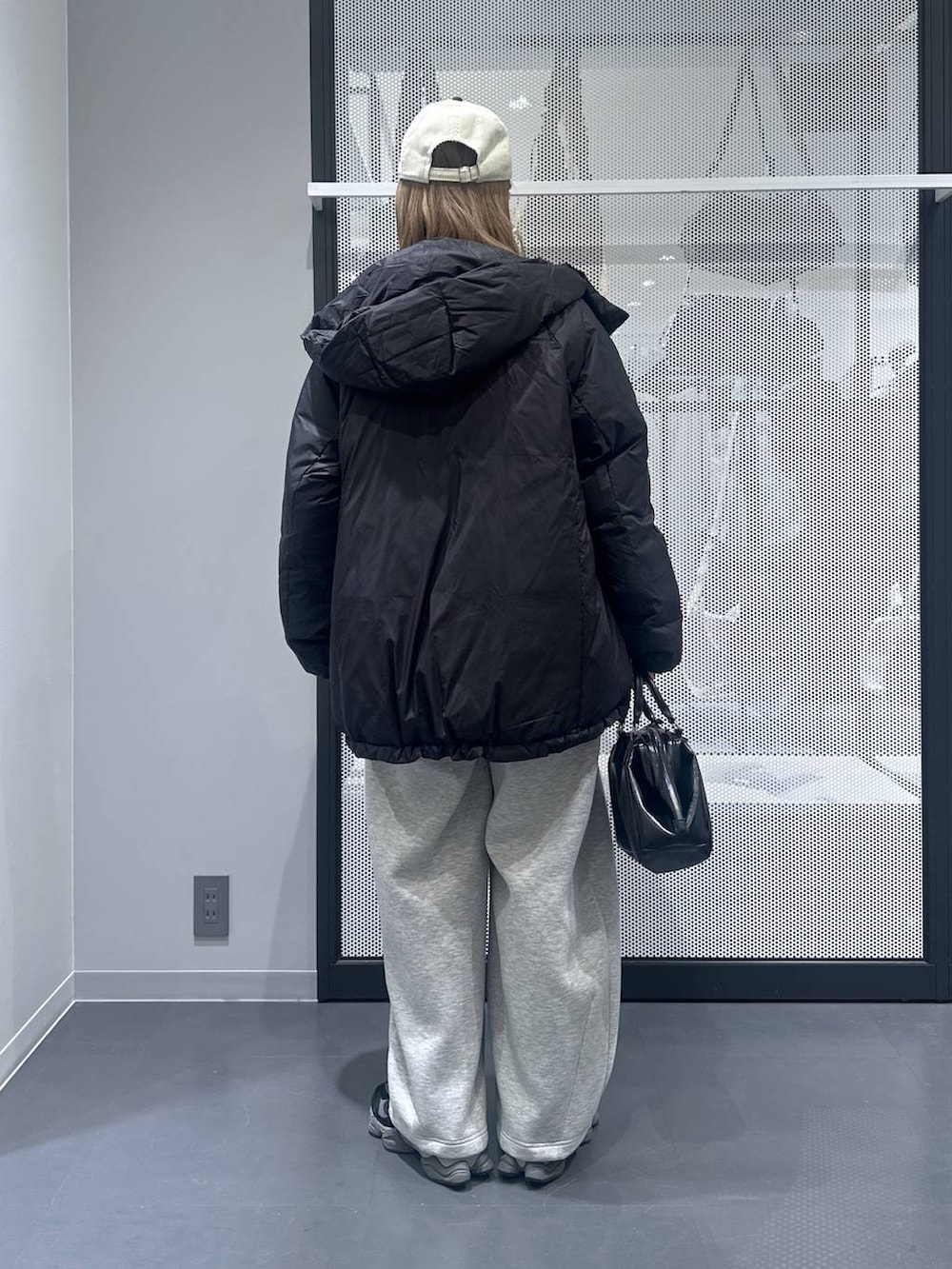 ブラック系のダウンジャケット/コート、ブラック系のショルダーバッグ、グレー系のスウェットパンツを着用したレディースの冬コーディネートの2枚目の写真