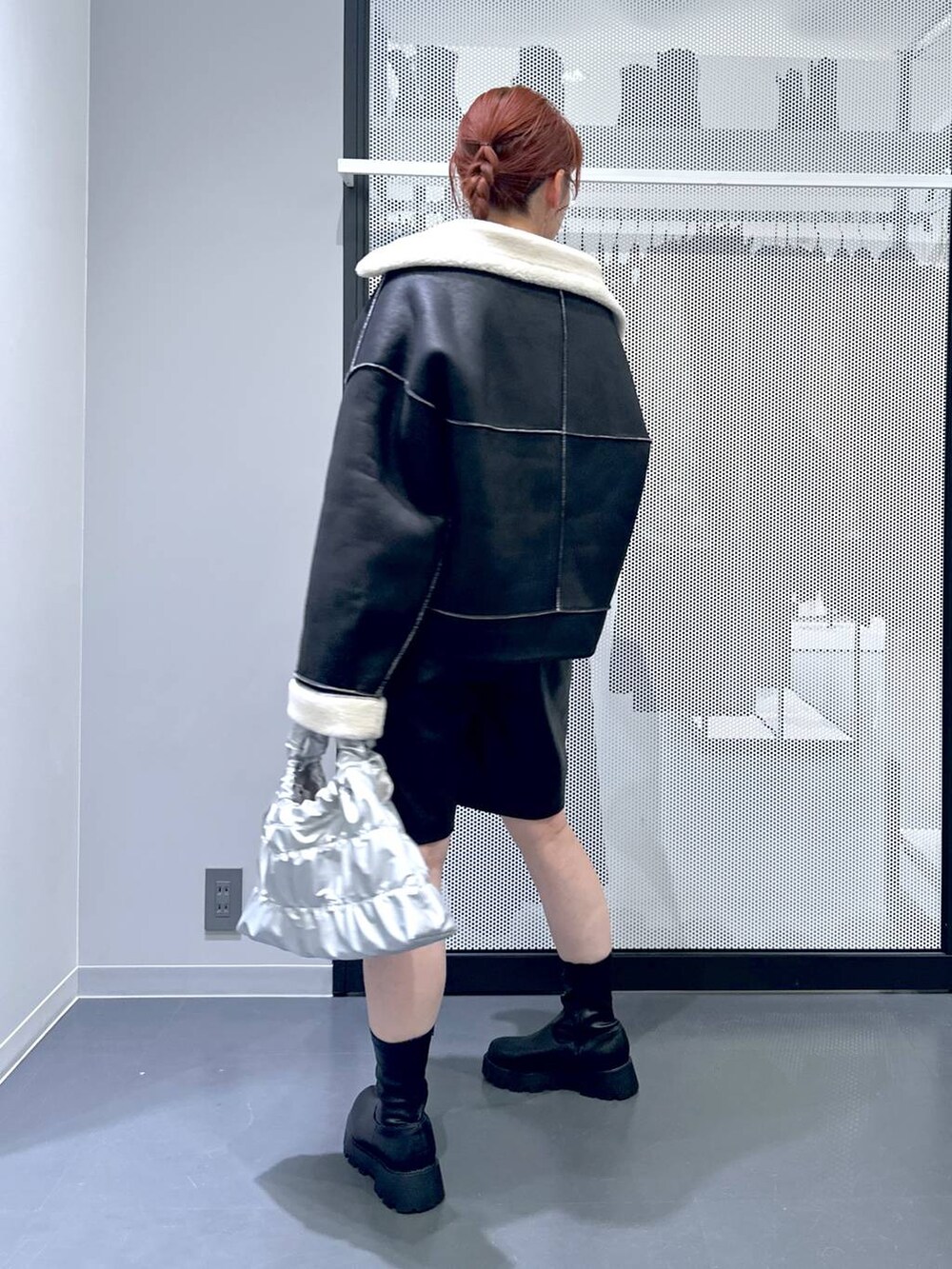 ブラック系のブルゾン、ブラック系のブーツ、シルバー系のショルダーバッグを着用したレディースの秋コーディネートの5枚目の写真