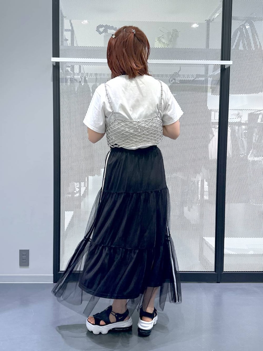 ブラック系のショルダーバッグ、ホワイト系のTシャツ/カットソー、ブラック系のスカートを着用したレディースの夏コーディネートの3枚目の写真