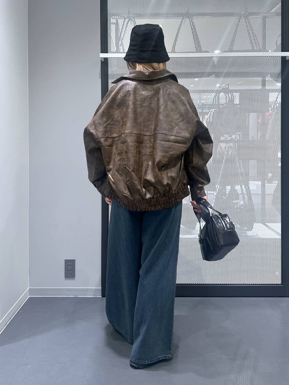 ブラウン系のブルゾン、ブラック系のショルダーバッグ、ブルー系のデニムパンツを着用したレディースの秋コーディネートの3枚目の写真