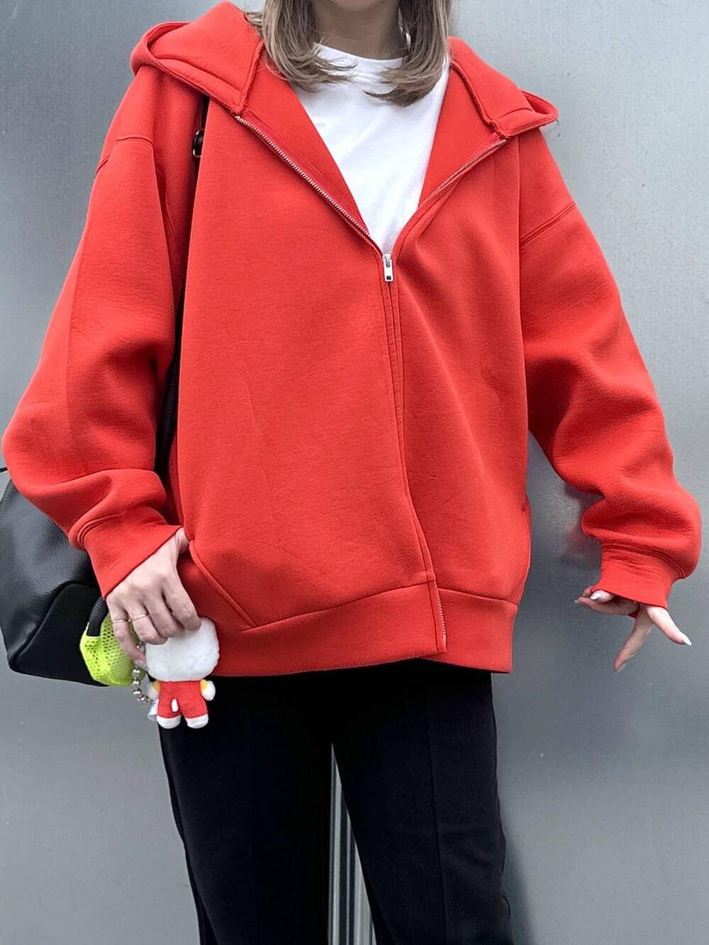 ブラック系のショルダーバッグ、レッド系のパーカー、ブラック系のその他パンツを着用したレディースの秋コーディネートの4枚目の写真