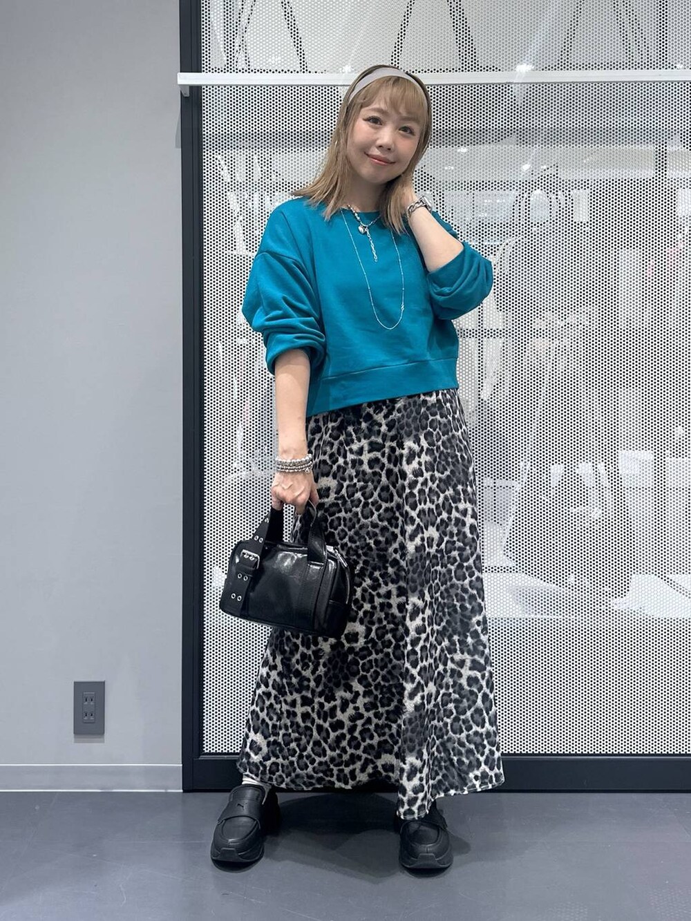 ブラック系のショルダーバッグ、グレー系のスカート、ブルー系のスウェットを着用したレディースの秋コーディネートの2枚目の写真