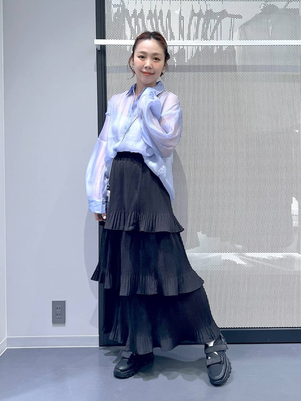 ブラック系のスニーカー、ブラック系のスカート、ブルー系のシャツ/ブラウスを着用したレディースの春コーディネートの2枚目の写真