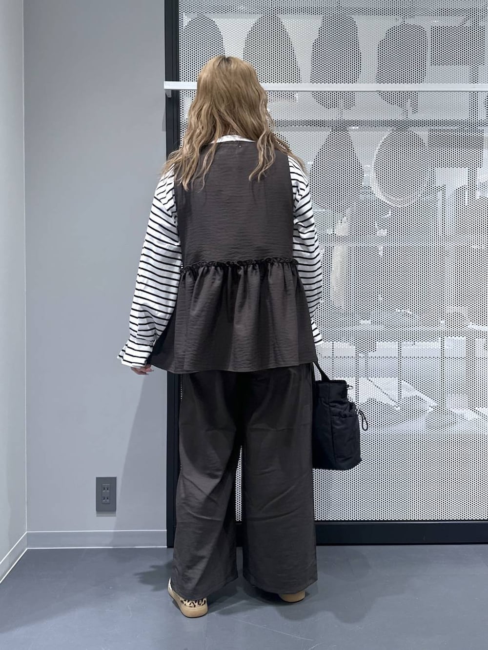 グレー系のその他パンツ、ブラック系のトートバッグ、ベージュ系のスニーカーを着用したレディースの春コーディネートの3枚目の写真