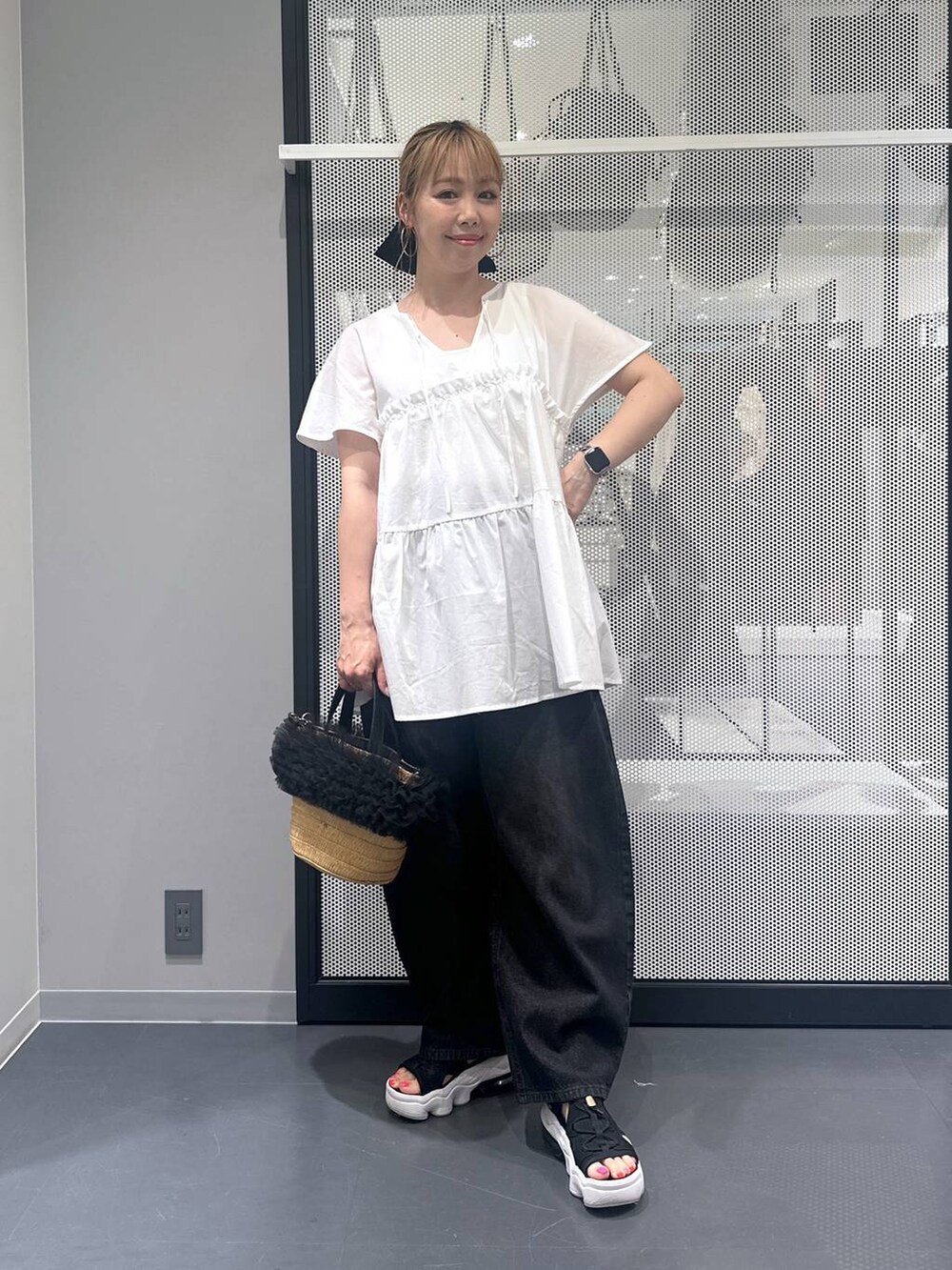 ブラック系のデニムパンツ、ベージュ系のショルダーバッグ、ホワイト系のタンクトップを着用したレディースの夏コーディネートの5枚目の写真