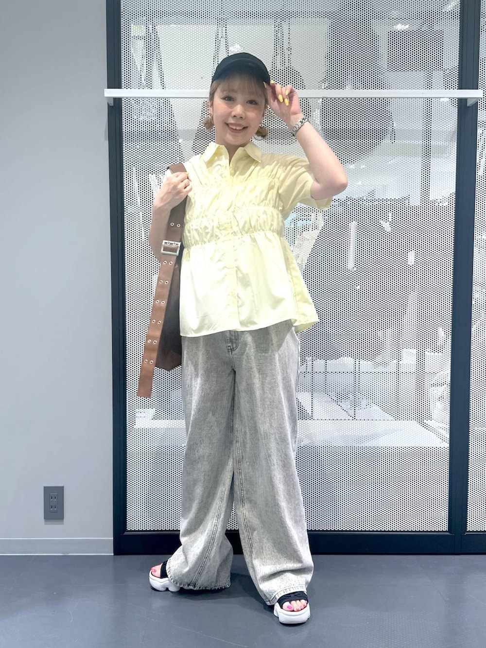 グレー系のデニムパンツ、ブラウン系のショルダーバッグ、イエロー系のシャツ/ブラウスを着用したレディースの夏コーディネートの5枚目の写真