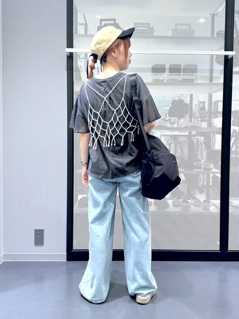 ブラック系のショルダーバッグ、ブルー系のデニムパンツ、ホワイト系のベストを着用したレディースの夏コーディネートの4枚目の写真