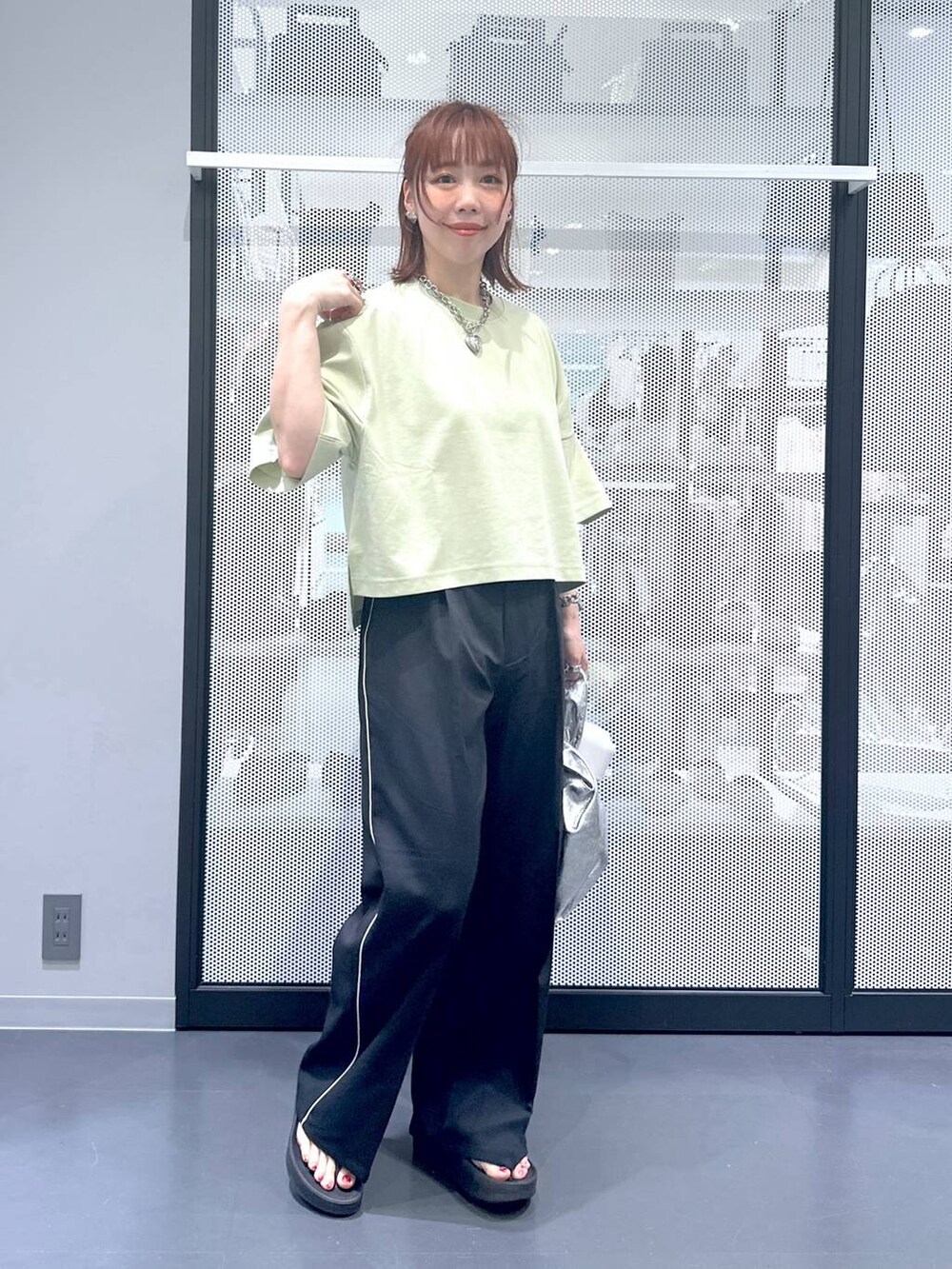 シルバー系のショルダーバッグ、グリーン系のTシャツ/カットソー、ブラック系のサンダルを着用したレディースの夏コーディネートの8枚目の写真