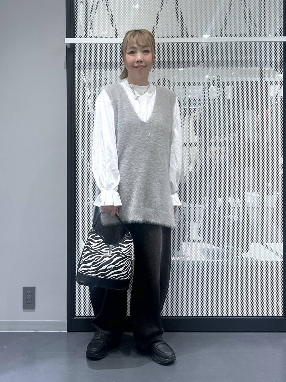 ブラック系のデニムパンツ、その他のショルダーバッグ、グレー系のベストを着用したレディースの秋コーディネートの2枚目の写真