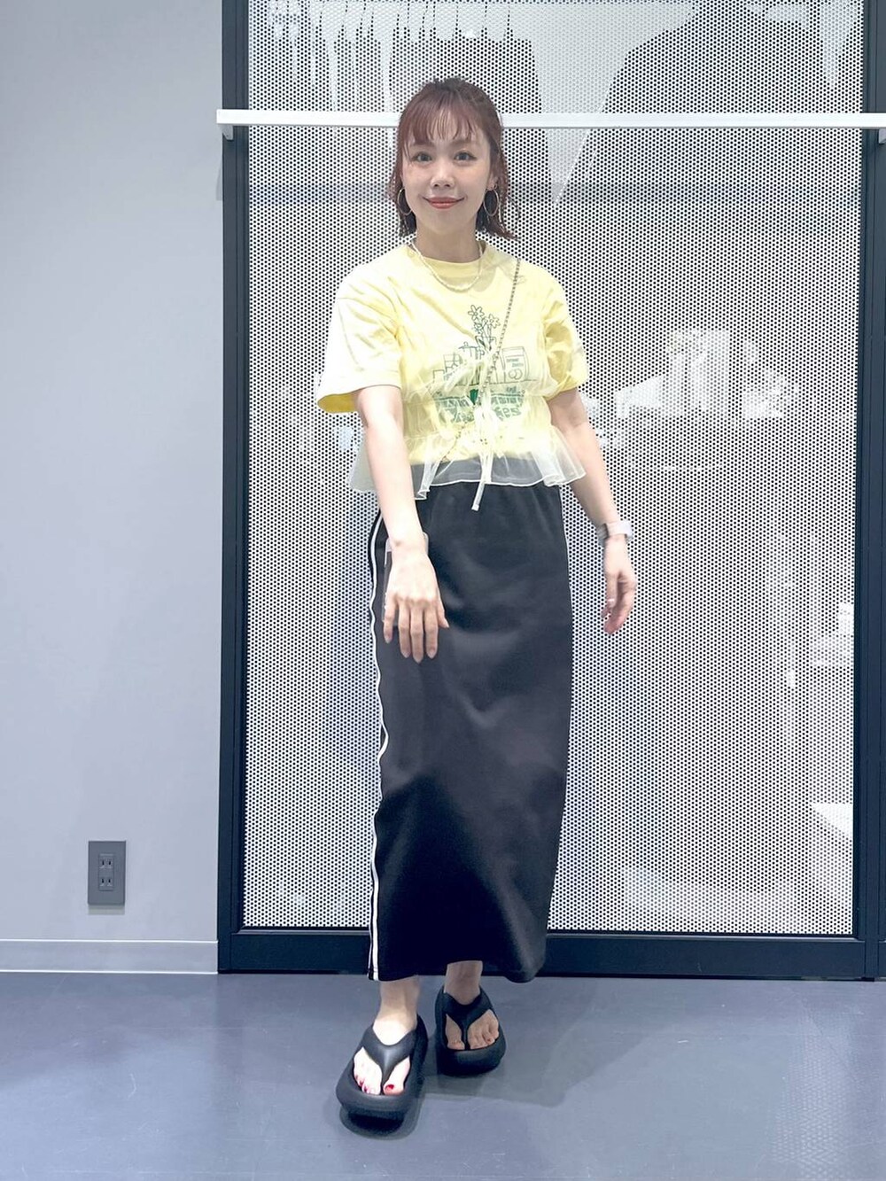 ブラック系のスカート、イエロー系のキャミソール、ベージュ系のTシャツ/カットソーを着用したレディースの春コーディネートの5枚目の写真