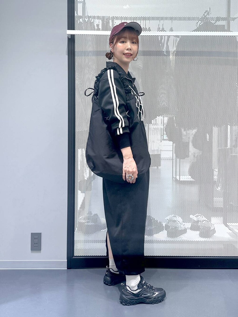 グレー系のスニーカー、ホワイト系のベスト、ブラック系のショルダーバッグを着用したレディースの秋コーディネートの3枚目の写真