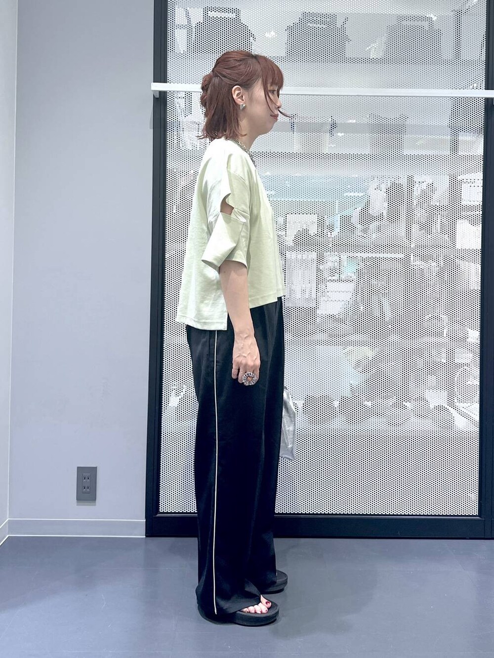 シルバー系のショルダーバッグ、グリーン系のTシャツ/カットソー、ブラック系のサンダルを着用したレディースの夏コーディネートの3枚目の写真