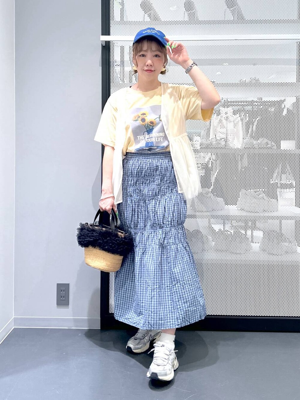 ベージュ系のショルダーバッグ、イエロー系のTシャツ/カットソー、ブルー系のスカートを着用したレディースの春コーディネートの2枚目の写真