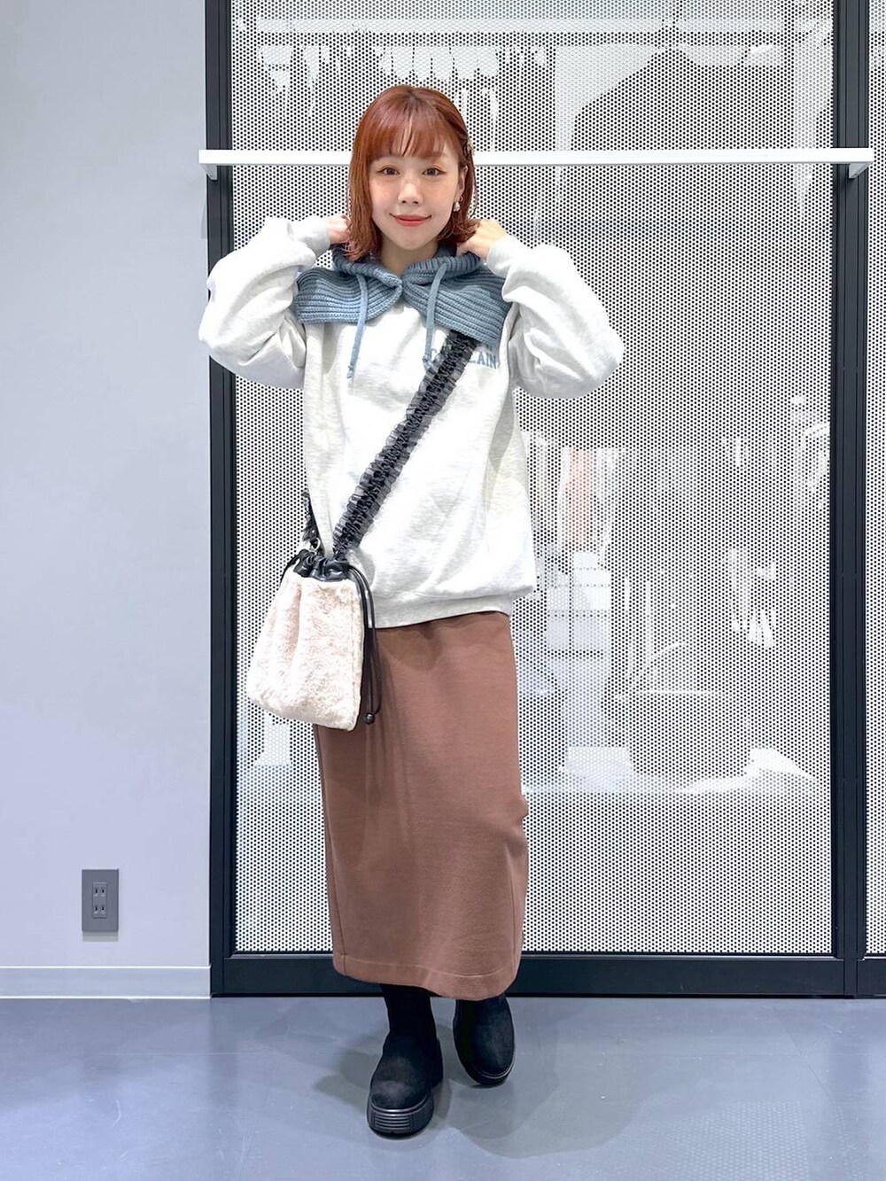 ベージュ系のショルダーバッグ、ブラウン系のスカート、ブラック系のブーツを着用したレディースの冬コーディネートの7枚目の写真