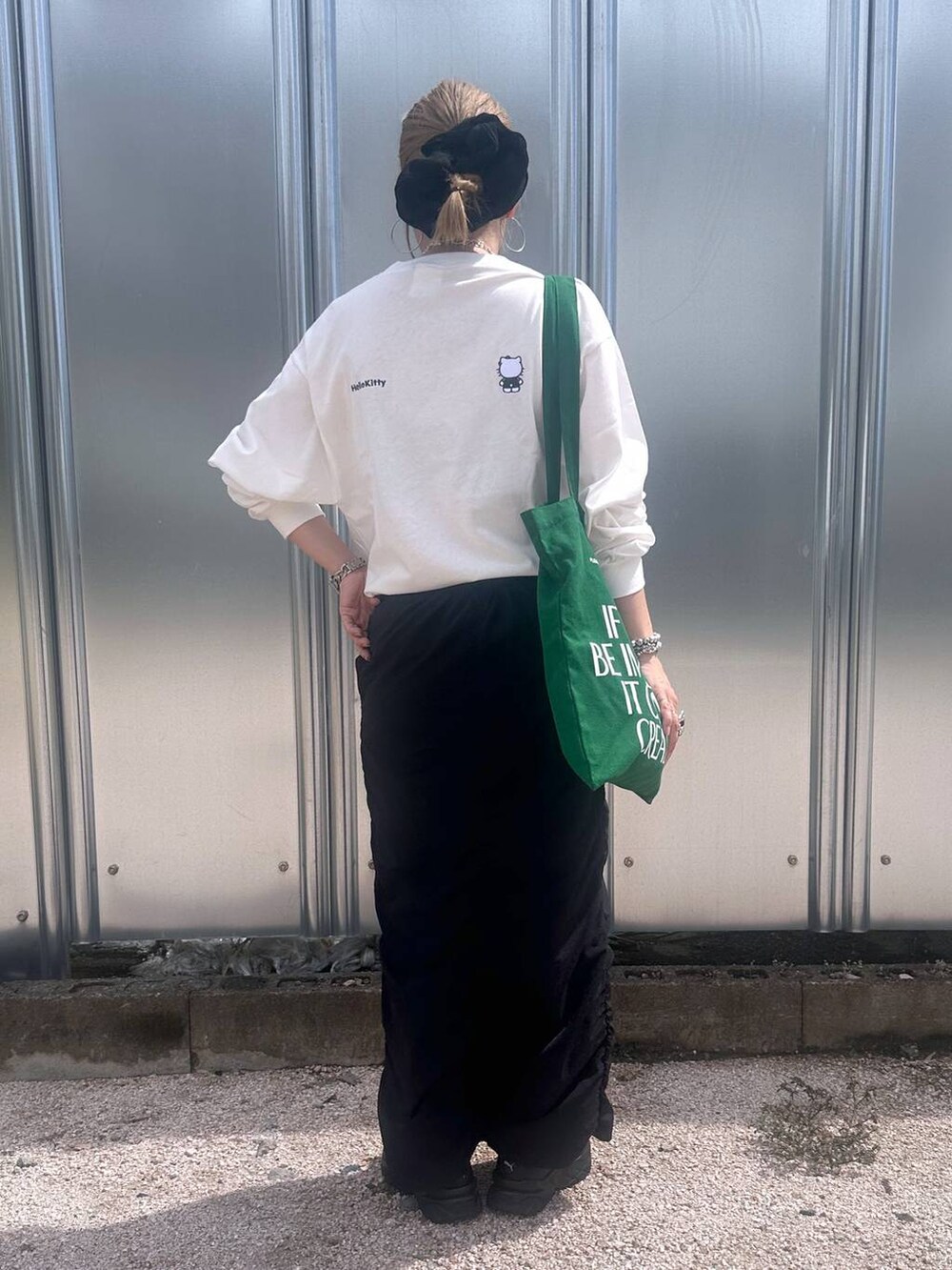 ブラック系のスカート、グリーン系のトートバッグ、その他のピアス(両耳用)を着用したレディースの秋コーディネートの2枚目の写真