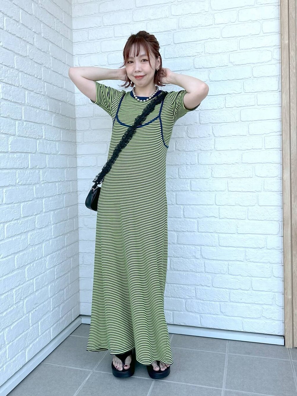 グリーン系のワンピース、ブラック系のサンダル、ブラック系のポーチを着用したレディースの春コーディネートの4枚目の写真