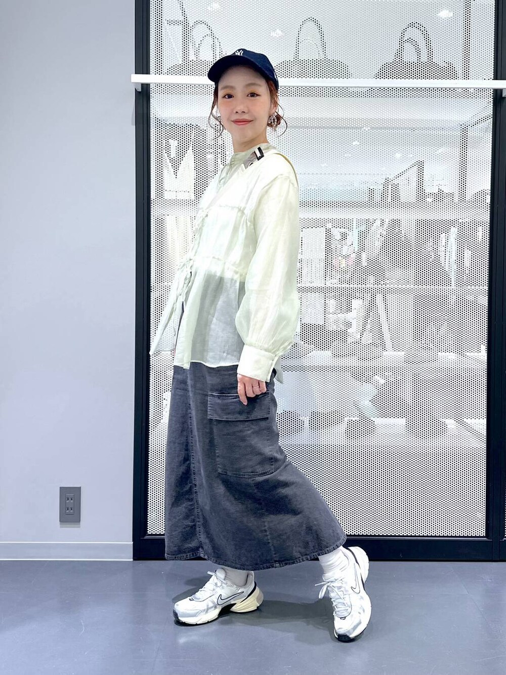 グレー系のデニムスカート、ホワイト系のTシャツ/カットソー、ホワイト系のショルダーバッグを着用したレディースの春コーディネートの9枚目の写真