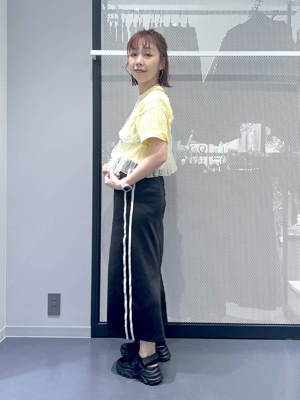 ブラック系のスカート、イエロー系のキャミソール、ベージュ系のTシャツ/カットソーを着用したレディースの春コーディネートの3枚目の写真