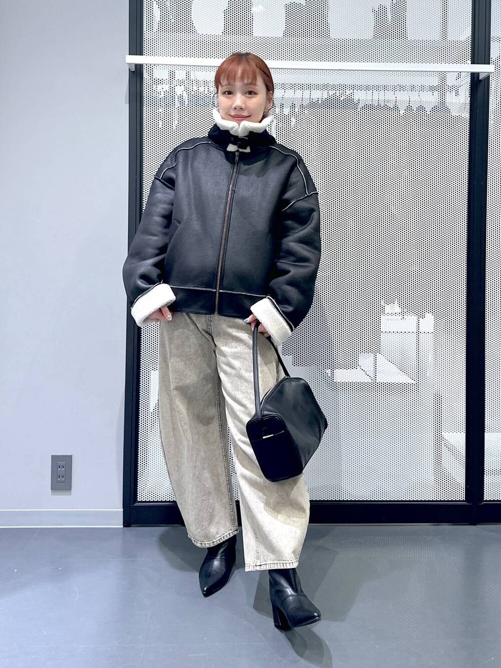 ブラック系のショルダーバッグ、ブラック系のブルゾン、ベージュ系のデニムパンツを着用したレディースの秋コーディネートの5枚目の写真