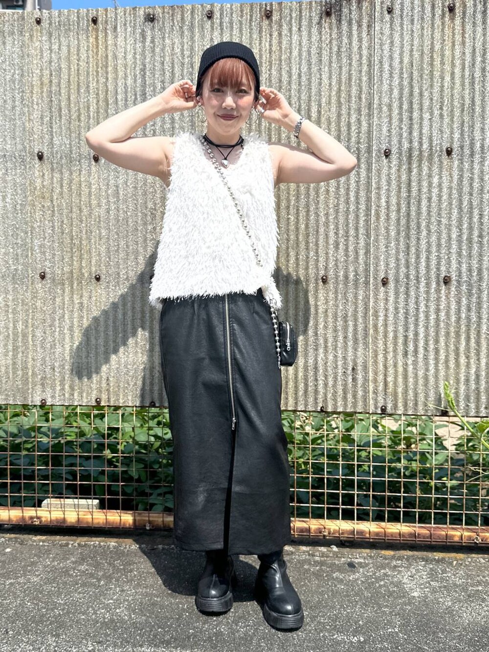 ブラック系のスカート、ブラック系のブーツ、ベージュ系のベストを着用したレディースの秋コーディネートの4枚目の写真