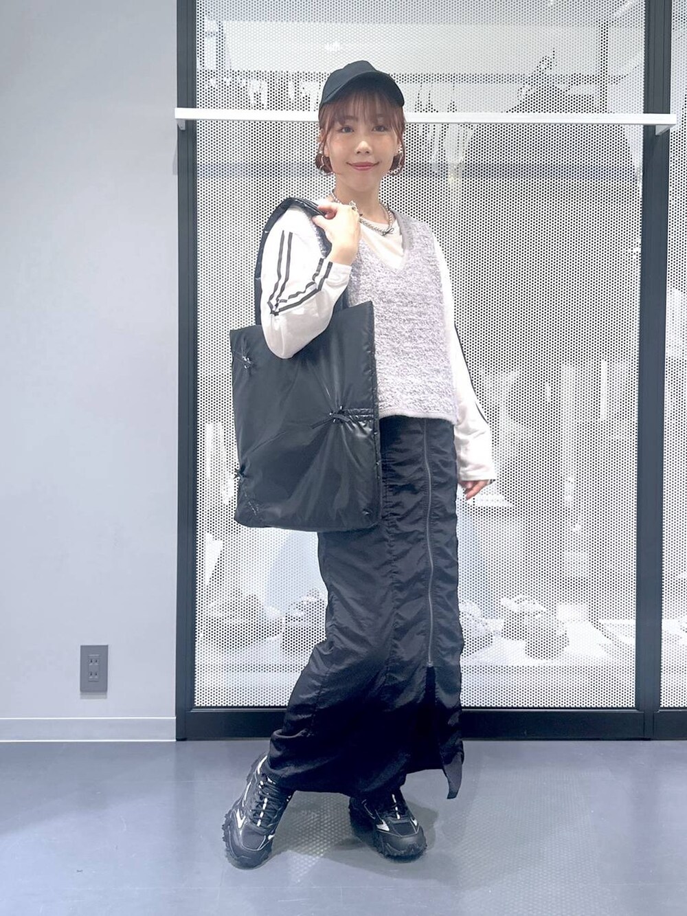 グレー系のスニーカー、ホワイト系のTシャツ/カットソー、グレー系のベストを着用したレディースの秋コーディネートの2枚目の写真