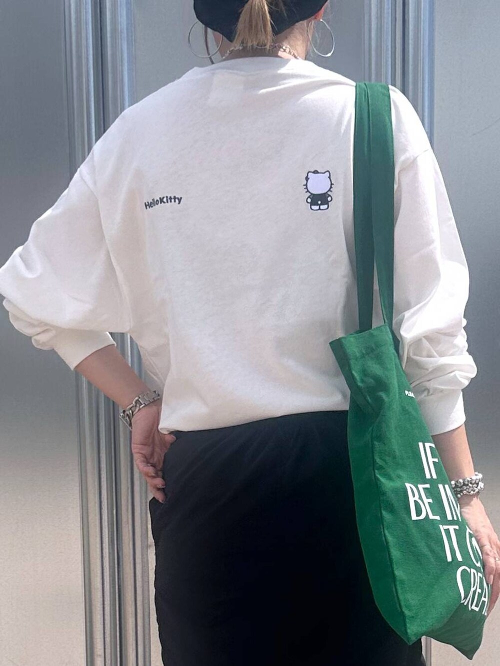 ブラック系のスカート、グリーン系のトートバッグ、その他のピアス(両耳用)を着用したレディースの秋コーディネートの4枚目の写真