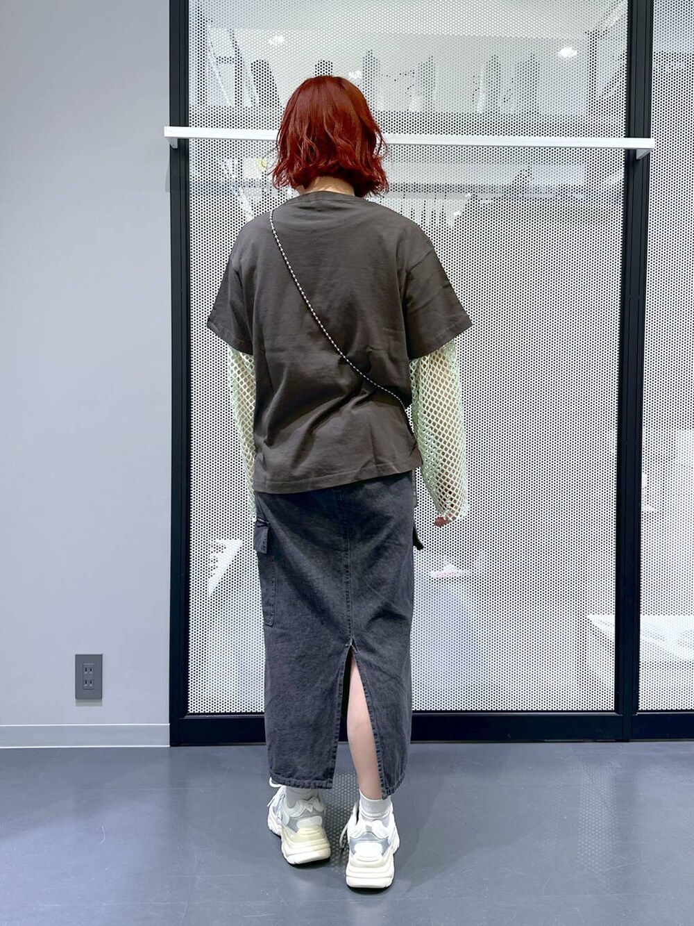 グレー系のデニムスカート、グリーン系のTシャツ/カットソー、ホワイト系のスニーカーを着用したレディースの春コーディネートの4枚目の写真