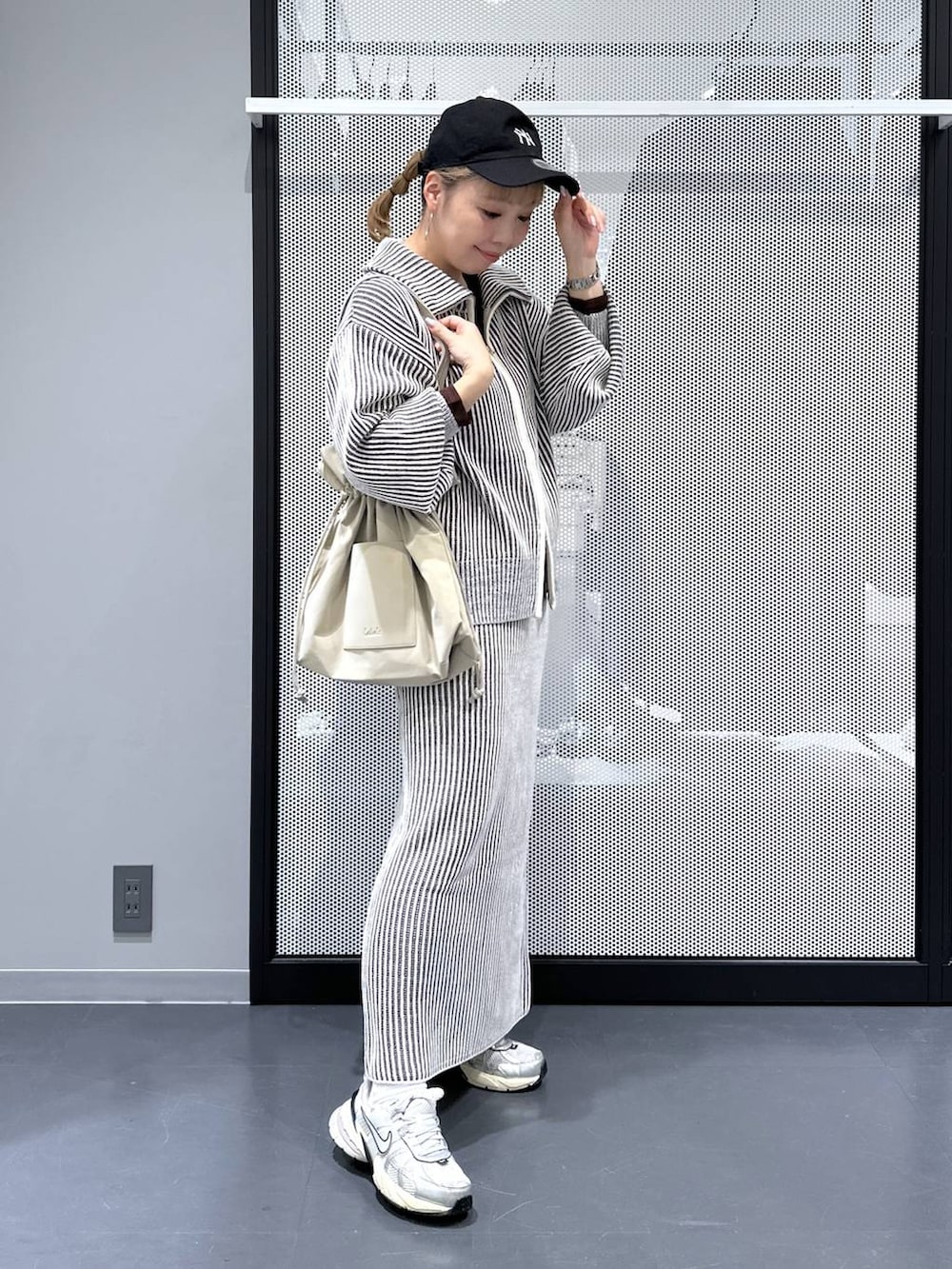 ベージュ系のトートバッグ、ベージュ系のスカート、ベージュ系のニット/セーターを着用したレディースの秋コーディネートの3枚目の写真