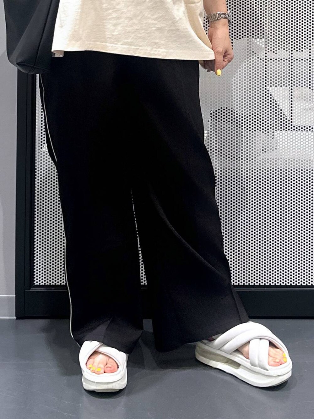 ブラック系のスラックス、ブラック系のショルダーバッグ、ブラック系のバレッタ/ヘアクリップを着用したレディースの夏コーディネートの5枚目の写真