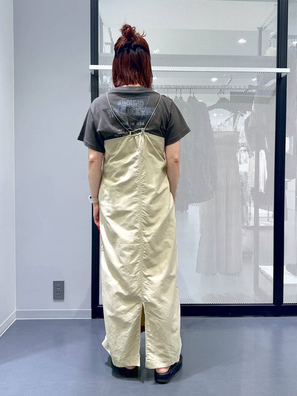 ベージュ系のワンピース、ブラック系のサンダル、グレー系のTシャツ/カットソーを着用したレディースの春コーディネートの4枚目の写真